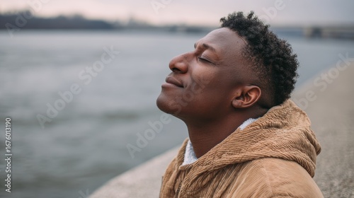 A young man enjoys the serene moment by the water, embracing the calmness and tranquility of nature.