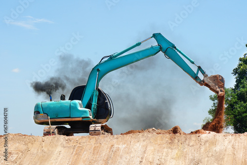 An excavator is operating and black smoke comes out of the exhaust pipe, which may indicate incomplete combustion of fuel.