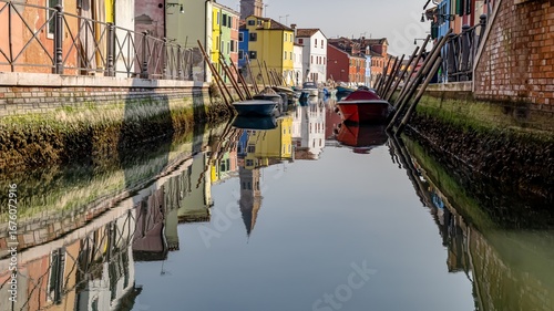 A canal in Burano, Venice, Italy, with a row of colorful buildings and boats.	