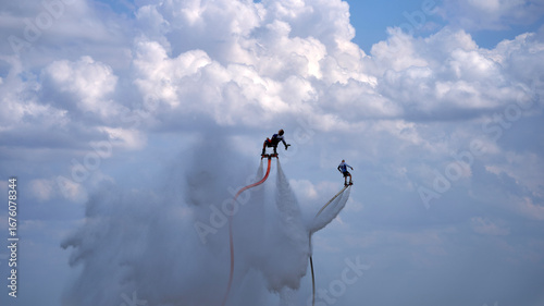 Two people are performing a water ski trick in the air