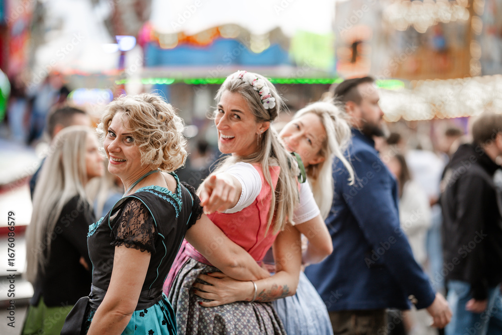 Fototapeta premium Three women wearing Bavarian dirndl costumes at cultural folk festivals like Munich Oktoberfest Gäubodenvolksfest in Straubing and Regensburg Dultfest Germany