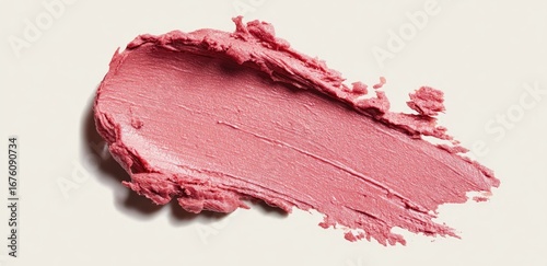 A swatch of pale pink lipstick or blush, textured and smudged, on a white background