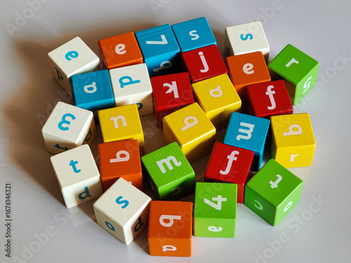 Colored wooden cubes, with letters and numbers on sides on grey background. Game childrens educational materials for learning process of making words from letters. Alphabet. ABC. Top view. Flat lay.