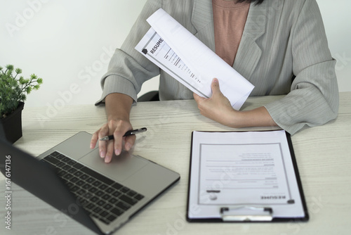 An asian businesswoman employer, Head of HR is holding resume, recruiting, planning, evaluating and reviewing resume of job applicant, recruiting new employees, recruitment, employment and HR concept.