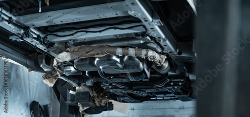 Automotive technician applying rustproof protective coating under a vehicle. Process helps prevent corrosion and extend vehicle lifespan. Ideal for illustrating car maintenance, vehicle care.