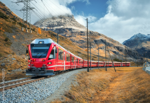 Εκτύπωση καμβά Red Bernina Express train passing through colorful autumn forest in the Swiss Alps, with dramatic clouds, golden trees and snowy mountain peaks in the background in Switzerland
