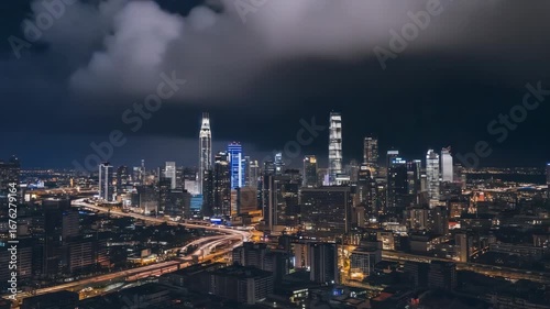 Wallpaper Mural Kuala lumpur city skyline is illuminating the night sky with busy roads and traffic trails, while dark clouds loom overhead, creating a dramatic and vibrant urban scene Torontodigital.ca