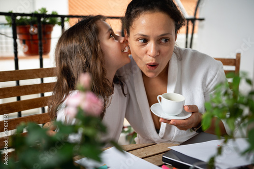 Mother and Daughter Sharing a Secretive Moment Over Morning Coffee on Balcony