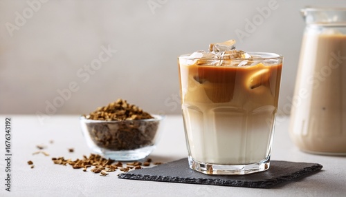 iced hojicha latte in clear glass with layered milk and roasted tea served on light modern surface selective focus