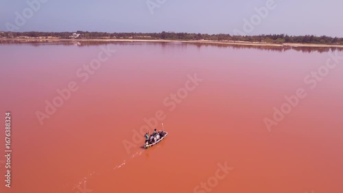 SENEGAL - 7.14.2025 - Stunning aerial view following a man as he rows a boat down Dakar, Senegal's Pink Lake.