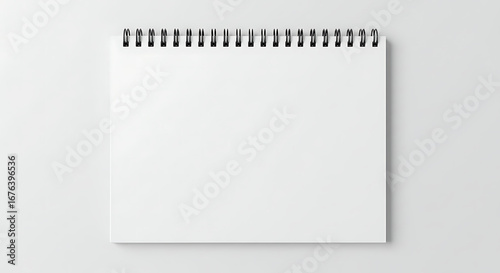 Blank white spiral-bound notebook with black wire binding open to a clean page top view.