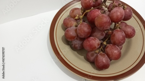 red grapes on a plate with a white background
