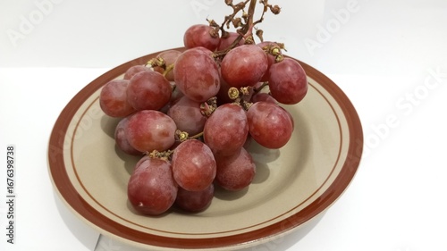 red grapes on a plate with a white background