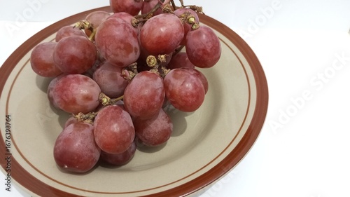 red grapes on a plate with a white background