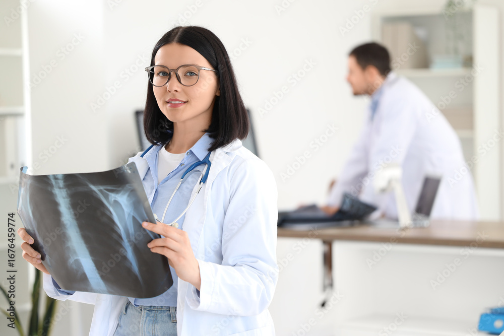 Fototapeta premium Female doctor with x-ray image of lungs in clinic