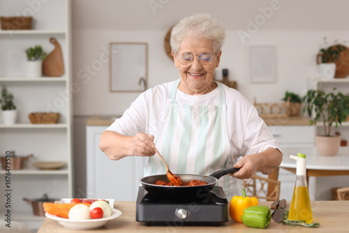 Senior woman frying food in...