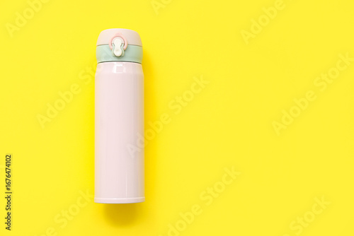 Modern pink thermos on yell...