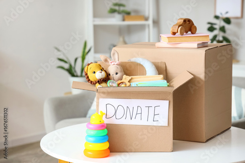 Donation boxes with children's toys and books on table in living room