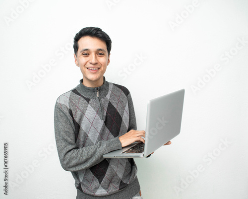 Joven hombre feliz mirando a la camara mientras sostiene su laptop en un fondo blanco aislado