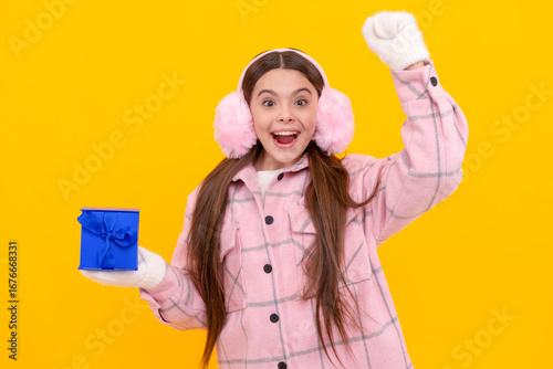 merry christmas. surprised happy kid in winter earmuffs with box. teen girl in mittens