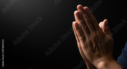 Closeup of hands clasped in prayer against a dark, moody background, symbolizing faith and hope