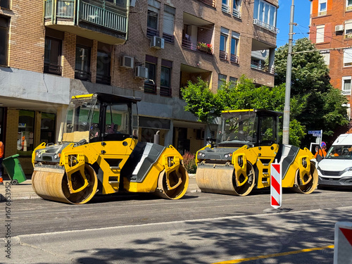 Row of road rollers on a city street. Heavy construction equipment, infrastructure, and maintenance work in urban settings.