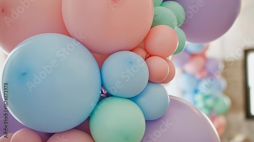 Close-up of pastel balloons forming an arch, with pink, blue, green, and purple hues