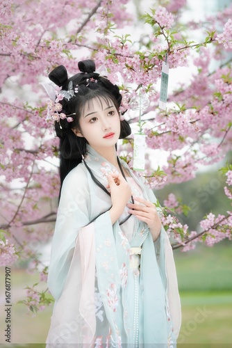 Young woman in a light blue hanfu among pink cherry blossoms Chinese word means cherry blossoms.