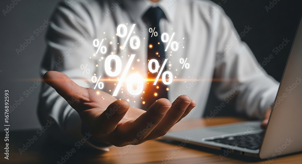 Naklejka premium A man in a white shirt holding percentage symbols above his hand with a laptop on the desk near him
