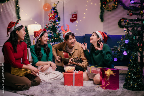 Fotografi Group of friends singing christmas carols while playing acoustic guitar at home