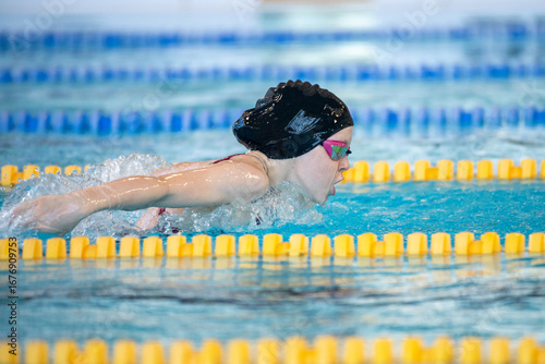 Swimmer girl swims butterfly swimming style in the pool