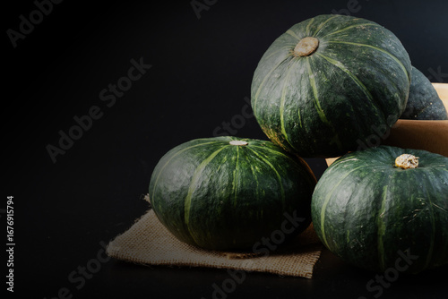 Fresh green pumpkins displayed on sackcloth with black background, natural vegetable concept for organic food, agriculture, harvest, healthy diet, and culinary design, perfect for creative projects.