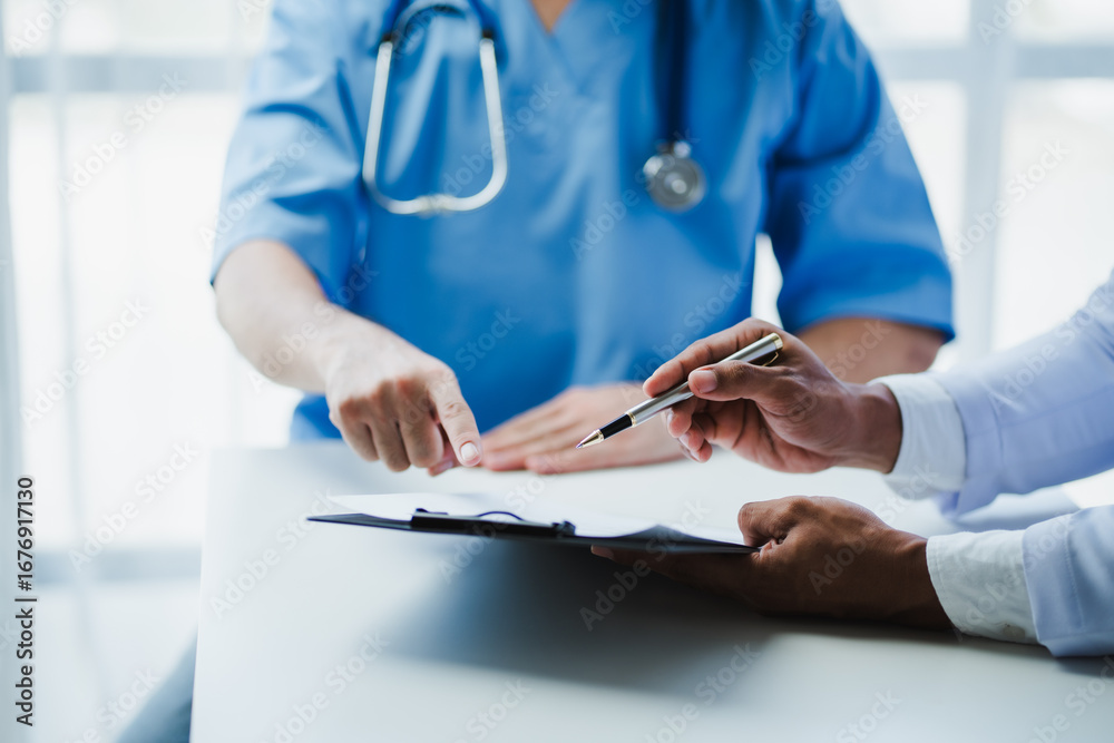 Fototapeta premium Doctors discussing medical report and pointing at clipboard
