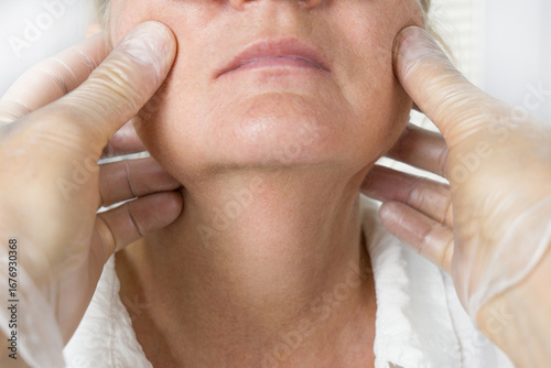 Doctor examine older woman face wearing gloves