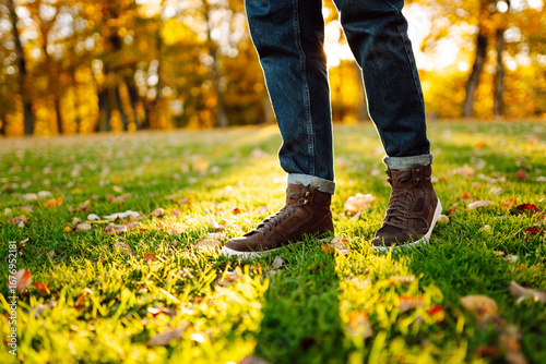 Fotografie A close-up of a man in boots walking along a path strewn with bright autumn leaves