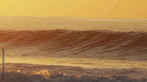 Male surfer sit on his surfboard in Indian Ocean at sunset time. Powerful wave crashing behind his body.Maldives