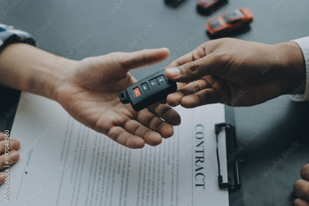 Fototapeta premium Car salesman gave the keys to the customers who signed the purchase contract legally, Successful completion of car sales, Purchase contract and key delivery.