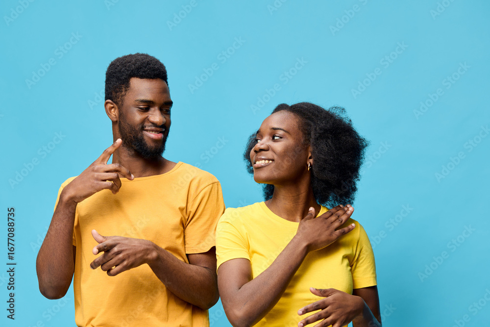 Obraz premium Cheerful couple in matching yellow t shirts against a bright blue background, expressing joy and connection, perfect for lifestyle and relationship themes