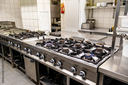 Fotografie Large stainless steel cooking range with ten active gas burners in commercial ki