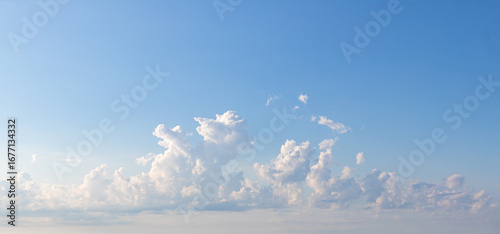 Sky replacement of blue sky and puffy white and gray clouds far in the horizon over a large body of water at sunset