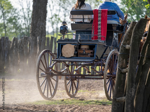A traditional horse-drawn carriage in motion, kicking up dust on a rustic country road. A classic rural travel and transport scene