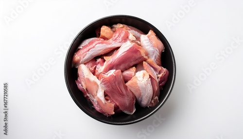 raw duck meat with skin pieces in black bowl n top view on white background