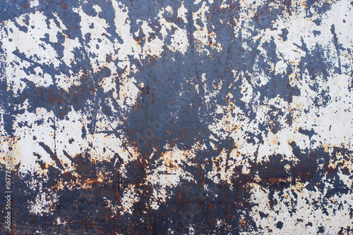 The walls are covered in peeling paint and have a rough texture. The blue color of the walls is faded and has a worn appearance. The walls have numerous cracks and holes.