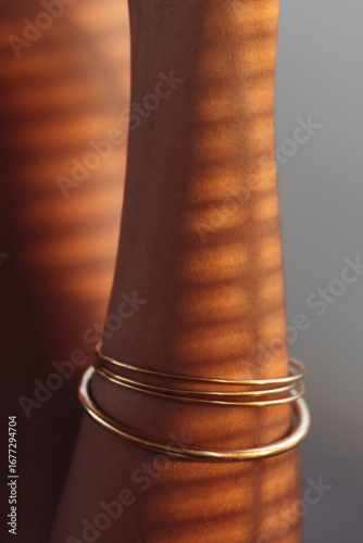 Close-up of mixed-race female skin with soft sunset light and striped shadows from window blinds, creating a warm and artistic atmosphere