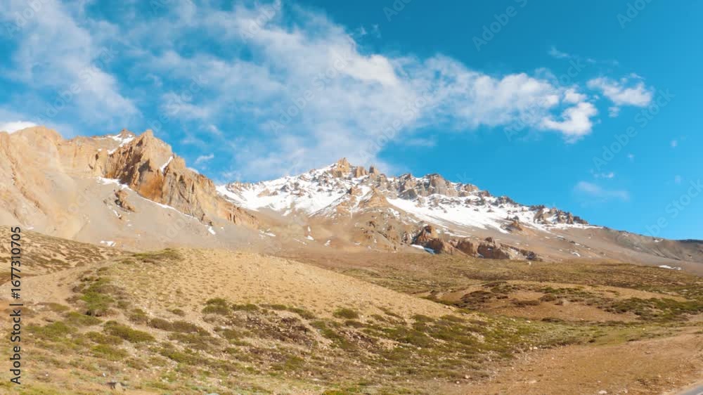Landscape shot of snowy Himalayan mountain peaks with clouds against the blue sky as seen from Sarchu in Leh Manali Highway, India. Scenic view of dry mountain peaks with snow on top at Ladakh. Landscape shot of snowy Himalayan mountain peaks with clouds against the blue sky as seen from Sarchu in Leh Manali Highway, India. Scenic view of dry mountain peaks with snow on top at Ladakh.