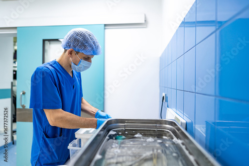 Surgical prep by medical staff. A healthcare worker in scrubs arranges surgical tools at a clean workstation in a bright operating room.