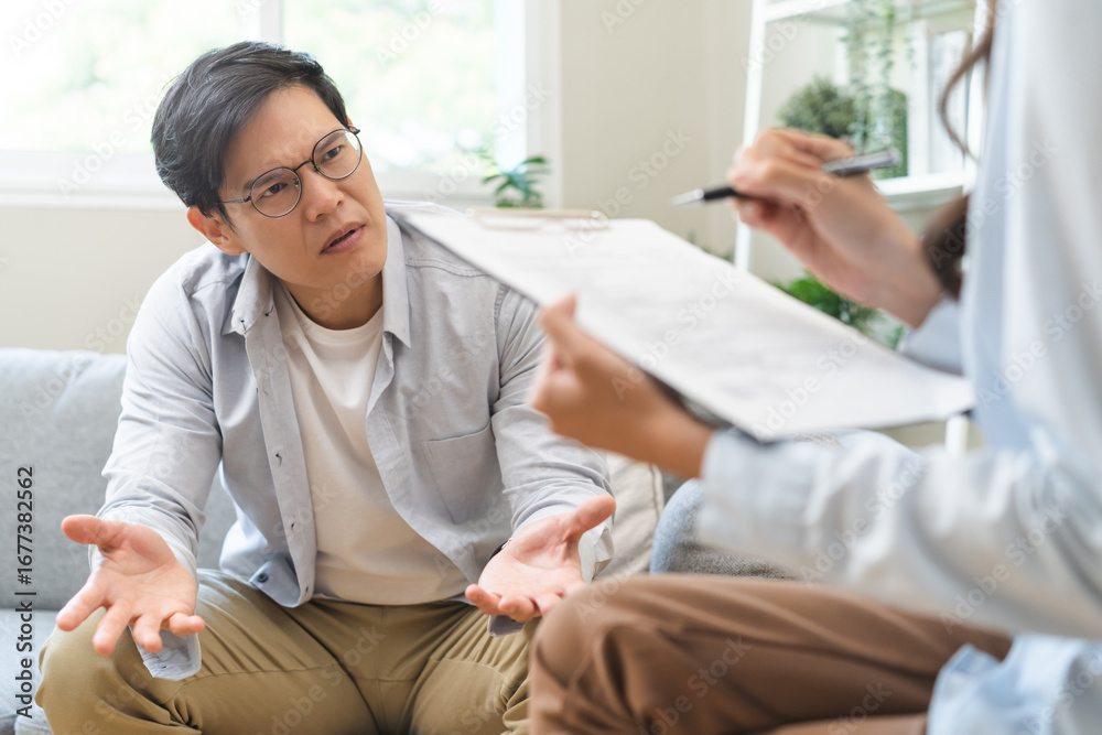 Obraz premium Psychology, depression. Sad, suffering asian young man, male consulting with psychologist, psychiatrist while patient counseling mental with doctor hand taking notes at clinic. Encouraging, therapy.