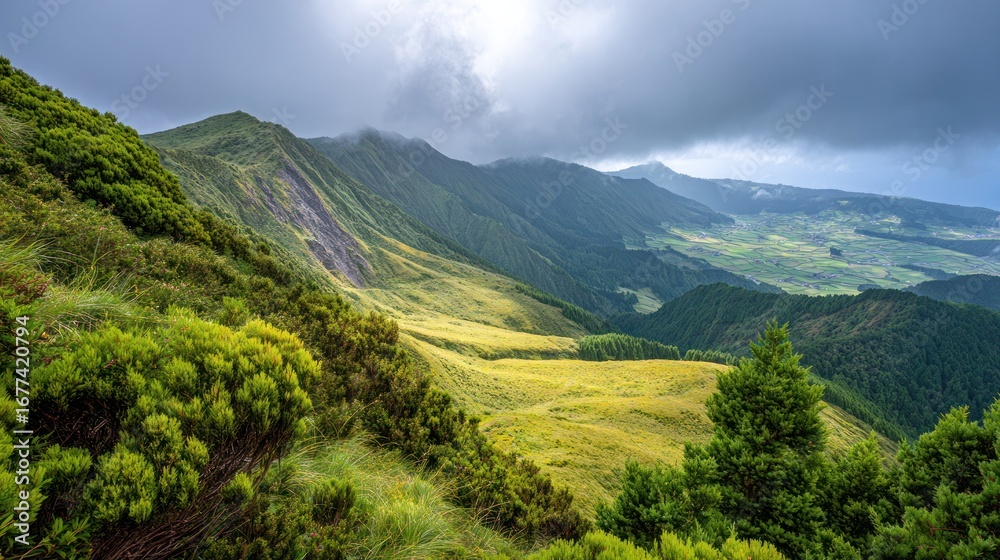 Fototapeta premium Serene Mountain Vista: A breathtaking vista of rolling green hills and majestic mountains stretches out under a dramatic, cloudy sky, creating a sense of vastness and tranquility.