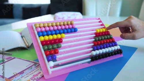 The little girl is counting on an abacus with her hand. Back to school concept.