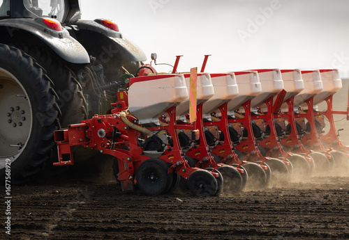 Farmer with tractor seeding in sunset